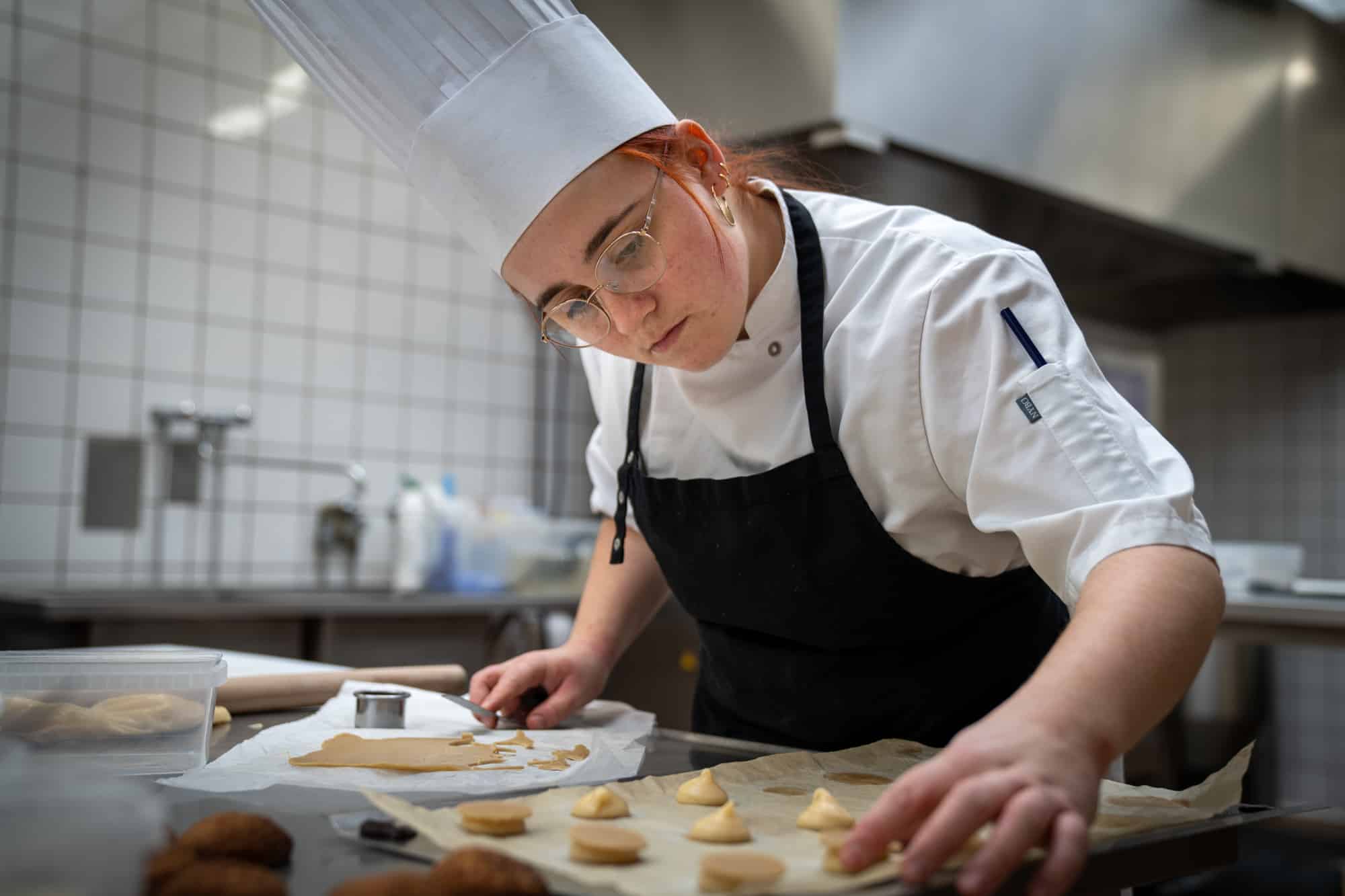 Kok tjekker om små kager på bageplade er bagt ordenligt